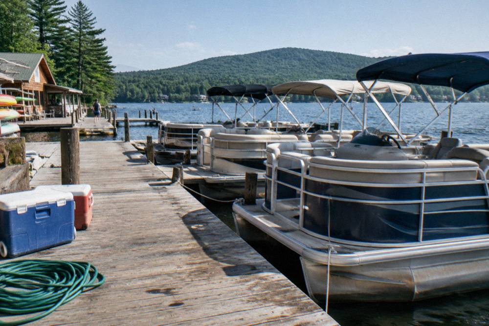 Rental pontoon boats tied to a wooden dock on Deep Creek Lake on a bright morning