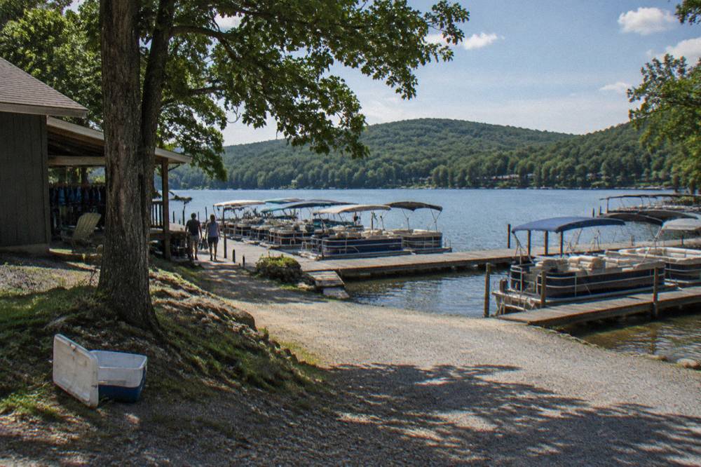 Rental pontoon boats tied along a dock at a lake marina