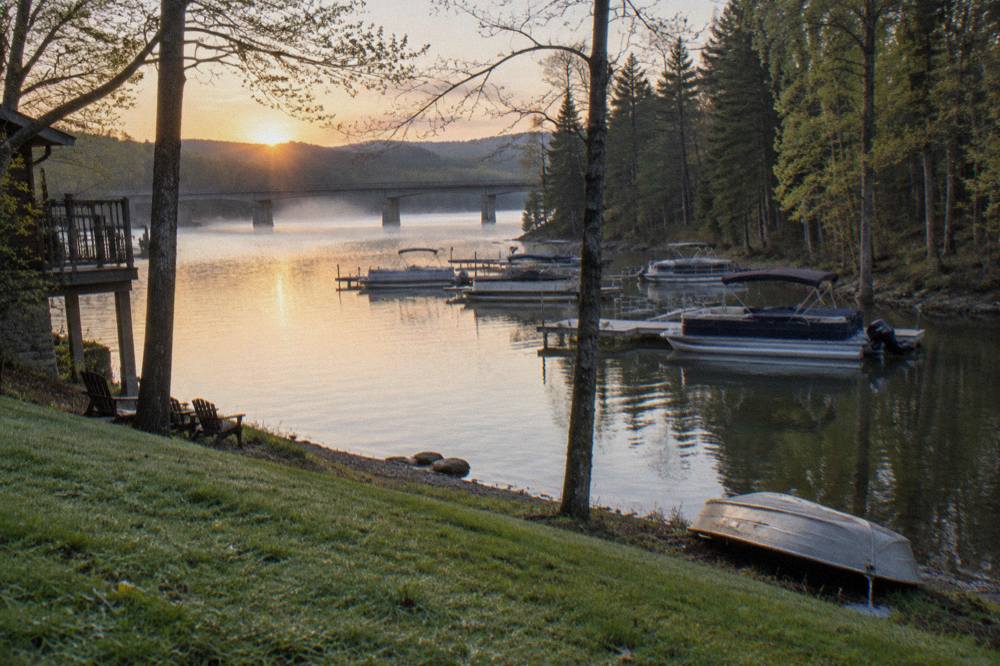 Pontoon boats moored along a wooded shoreline of a mountain lake in morning light